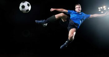 Young soccer player leaping into air to kick ball